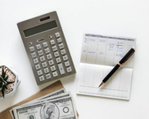 a checkbook, calculator, and money on a table