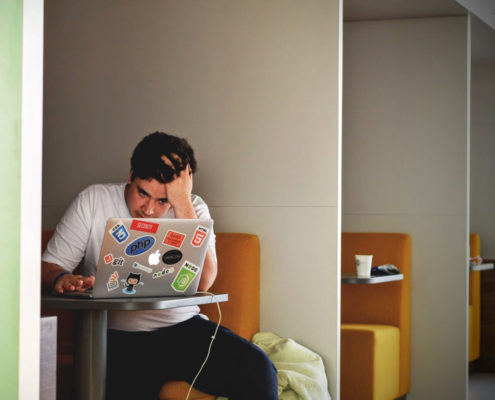 stressed man sitting at his laptop