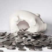 a whitee piggy bank lays on its side with coins falling out