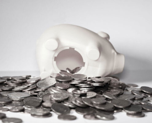 a whitee piggy bank lays on its side with coins falling out